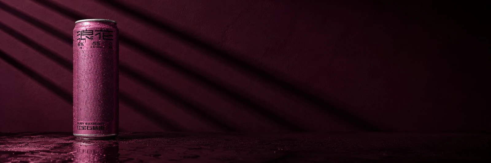 A Langhua Ruby Waxberry can lit against a deep ruby wall, shadow bands falling across the surface